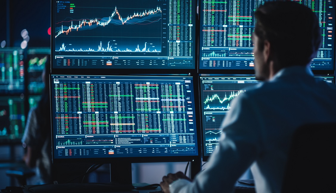 Man looking at computers executing stock trades